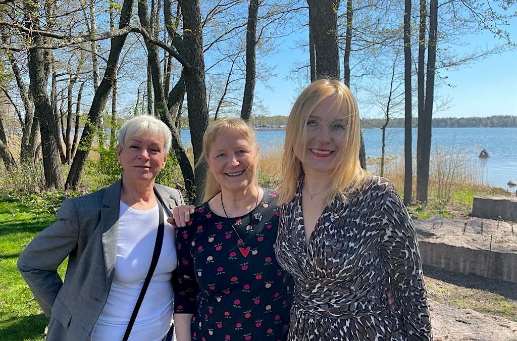 kolme rotary-naista taustalla keväinen merinäköala ja puita